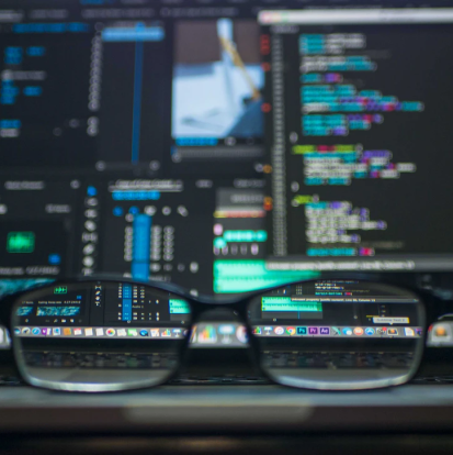 Um oculos na frente de um monitor com a tela desfocada